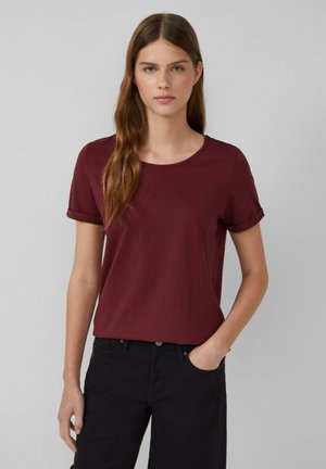 T-shirt bourgogne à manches courtes avec un col rond, fabriqué en tissu doux. Équipe des manches retroussées et une coupe décontractée, associé à un pantalon noir.
