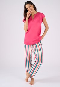 Rosa korte mouwen top met V-hals en zak, gecombineerd met meerkleurige gestreepte broek. De stof lijkt zacht en heeft een relaxed fit.