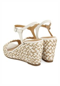 Sandalias de cuña blancas con tacón de yute trenzado, parte posterior abierta y tira al tobillo. Parte superior de cuero suave con interior a juego y cierre de hebilla.