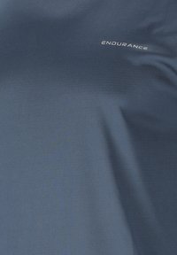 Dunkelblaue Stoffoberfläche mit leichter Textur und dem Wort „ENDURANCE“ in kleinen, hellgrauen Großbuchstaben nahe der oberen rechten Ecke gedruckt.