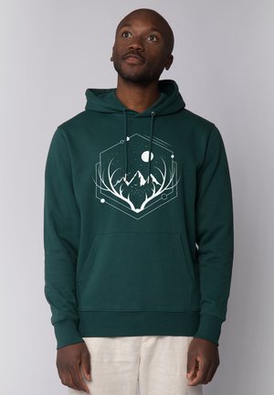 Dunkelgrüner Kapuzenpullover aus weichem Stoff. Mit einer Fronttasche und einem grafischen Design von Bergen und Geweihen in Weiß.