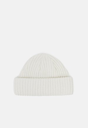 Valge kootud beanie, millel on keeratud äär ja vertikaalne soonikutekstuur. Pehme kangas, ümar ülaosa, sobib külmemate ilmade jaoks.