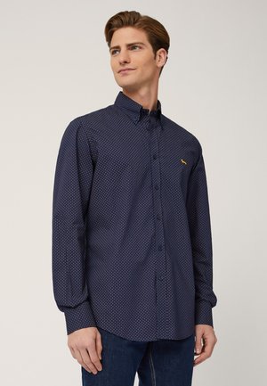 Camicia a maniche lunghe di colore blu navy con piccoli pois bianchi e rossi, caratterizzata da un colletto button-down e un accento con logo giallo.