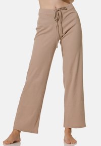 Pantalons larges beiges en tissu côtelé. Dotés d'une taille à cordon de serrage et d'une coupe décontractée, idéaux pour une tenue décontractée. Texture lisse.