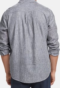 Herren-Hemd mit blauen und weißen vertikalen Streifen, langen Ärmeln, die an den Bündchen hochgekrempelt sind, aus weichem Stoff und mit einem leicht abgerundeten Saum.