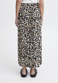 Maxiskirt med leopardprint i sort og brun på en cremefarvet baggrund, lavet af letvægtsstof med elastisk talje.