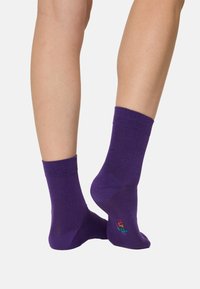 Lilla bomuldscrew-sokker med ribbede manchetter, der har et lille multicolor-logo nær hælen og en glat tekstur.