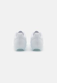 Zapatillas deportivas blancas con un upper sintético liso, cuello acolchado y suela transparente texturizada, que presenta un diseño minimalista.