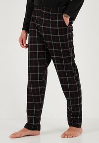 Pantaloni de lounge cu carouri negre, având un model în grilaj roșu și alb, talie elastică și buzunare laterale. Confecționați dintr-un material moale și texturat.