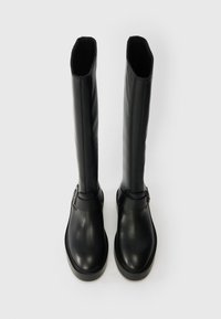 Botas pretas até ao joelho feitas de couro lisos, com biqueira redonda, sola plana e uma faixa decorativa com fechos de fivela.