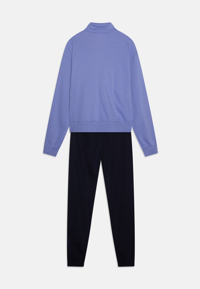 Felpa lilla chiaro con collo a imbuto e pantaloni blu scuro. Il materiale sembra morbido con una vestibilità rilassata e polsini a coste sulle maniche e sulle caviglie.