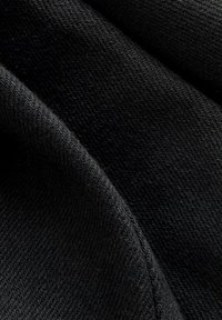 Schwarzer Stoff mit glatter Textur, der ein dezentes Webmuster aufweist. Das Material wirkt dehnbar und flexibel. Eine Nahaufnahme hebt die Details hervor.