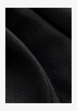 Sort stof med en glat tekstur, der har et subtilt vævemønster. Materialet ser strækbart og fleksibelt ud. Nærbillede fremhæver detaljerne.