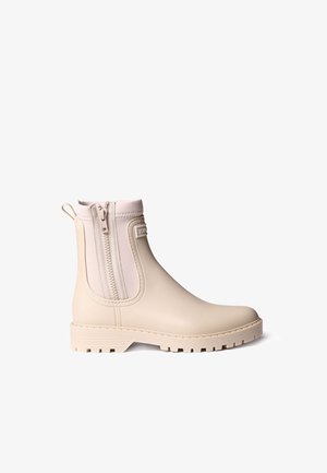 Botte de pluie beige couvrant la cheville avec fermeture éclair latérale, languette à l’arrière et semelle texturée pour une meilleure adhérence, présentée sur fond blanc.