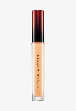 Kevyn Aucoin concealer in a clear tube with a frosted base and a gradient red to black cap, featuring bold black text on the side.