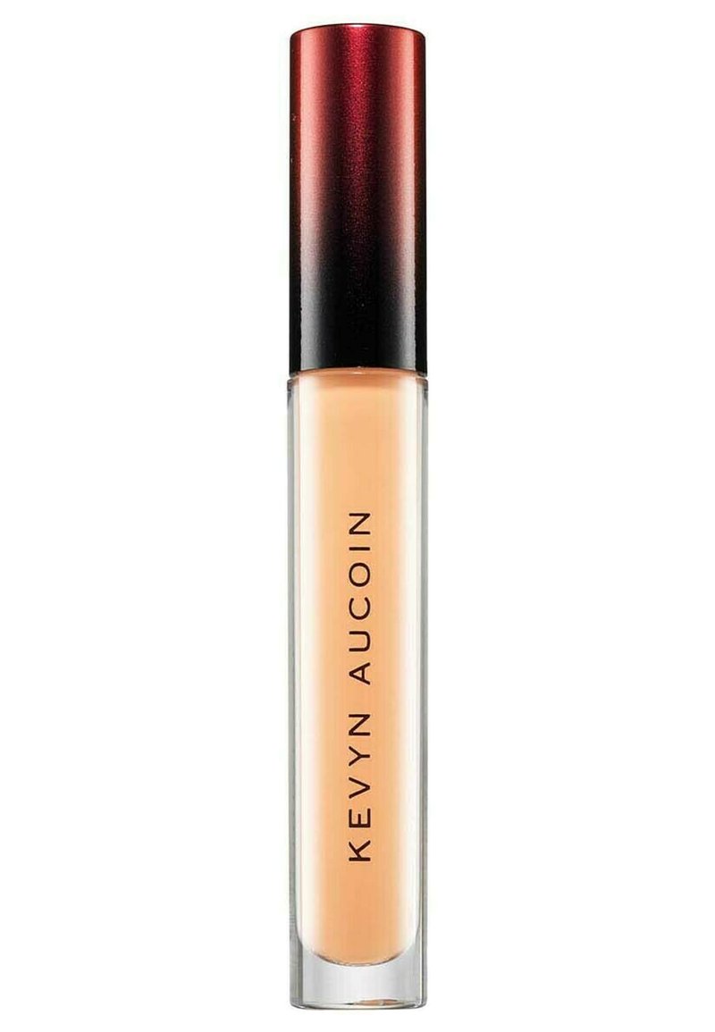 Correcteur Kevyn Aucoin dans un tube transparent avec une base givrée et un capuchon dégradé rouge à noir, présentant un texte noir audacieux sur le côté.