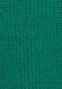 Pletená látka v živé tyrkysové barvě s texturovaným vzorem propojených stehů a měkkým, mírně chlupatým povrchem.