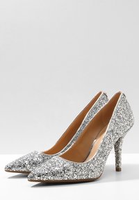 Escarpins argentés pailletés avec un design à bout pointu, une silhouette élégante, un talon aiguille et une doublure intérieure lisse couleur tan.
