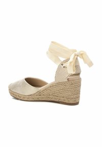 Wedge espadrille beige con una piattaforma in paglia testurizzata, nastri in raso alla caviglia e una punta morbida e lucida. Dettagli a motivo check sul tacco.