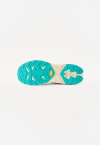 Suola di una scarpa con una superficie in gomma turchese, caratterizzata da un motivo di battistrada testurizzato, un'intersuola crema e un evidente dettaglio del logo in gomma gialla.