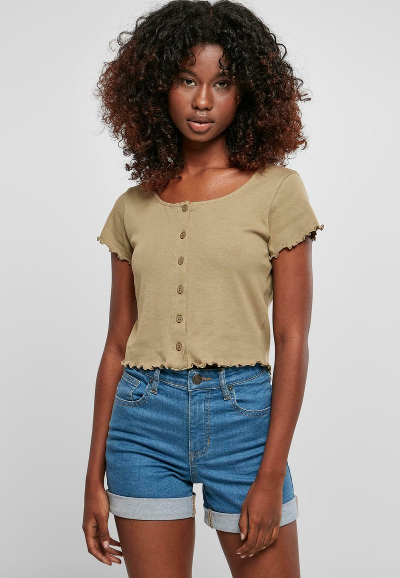 Haut court ajusté vert olive avec un décolleté rond et cinq boutons sur le devant. Bords froncés sur les manches et l'ourlet. Associé à un short bleu taille haute.