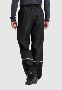 Zwarte waterdichte broek met een elastische tailleband, reflecterende strepen en ritsen bij de enkels. Gemaakt van lichtgewicht, duurzaam materiaal.