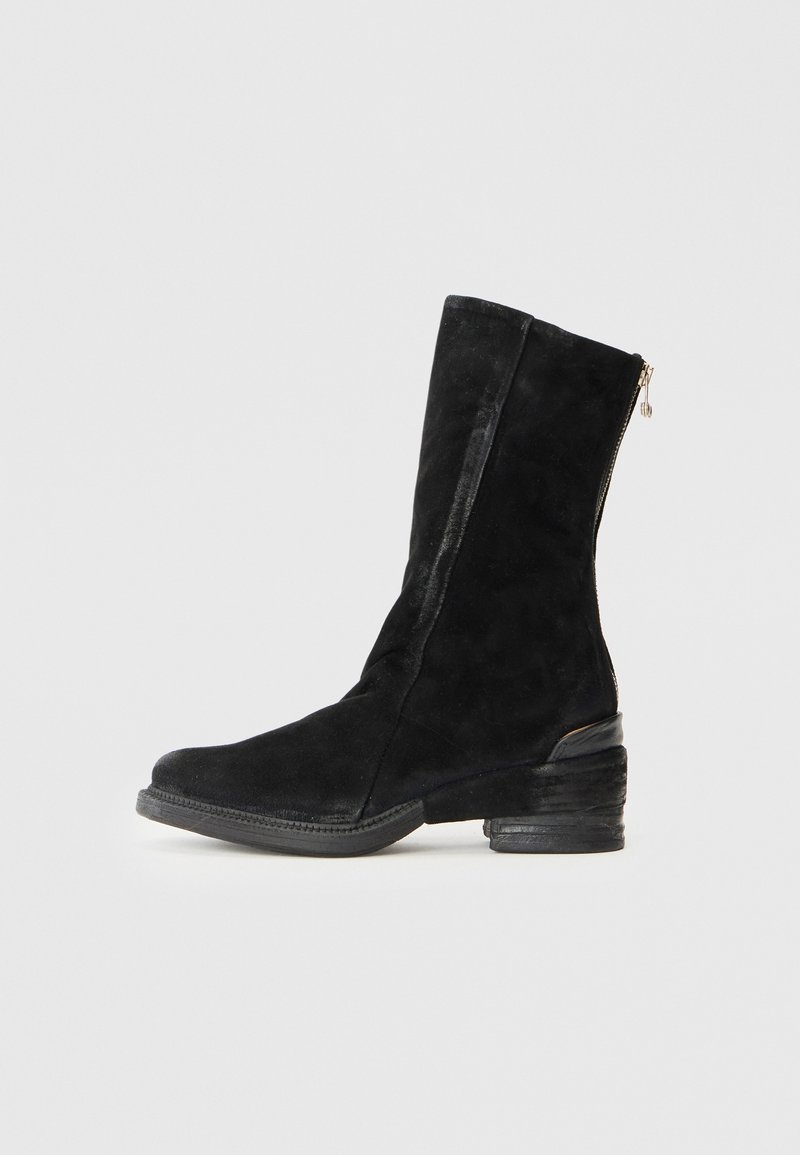 Stivale in suede nero a metà polpaccio con punta tonda, tacco impilato e zip dorata sul retro, su uno sfondo chiaro e semplice.