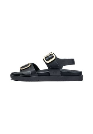 Sandalias negras de goma con dos hebillas ajustables. Presentan una suela plana y un diseño abierto, ideal para el clima cálido.