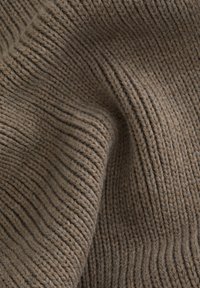 Brūns adīts audums ar redzamām ribu tekstūrām, maigs izskats un smalki punkti, kas izceļ siltu, zemes krāsu paleti.