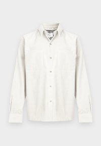 Pamut kordbársony ing törtfehér színben, hosszú ujjakkal, gombolható elülső résszel, két mellzsebbel és laza szabással, finom bordázottsággal.