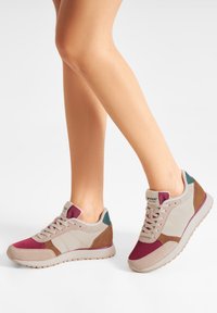Sneakers med en blandning av material som inkluderar mesh och mocka i beige, burgunder och teal. Har en texturerad baksida och en kontrasterande sula.