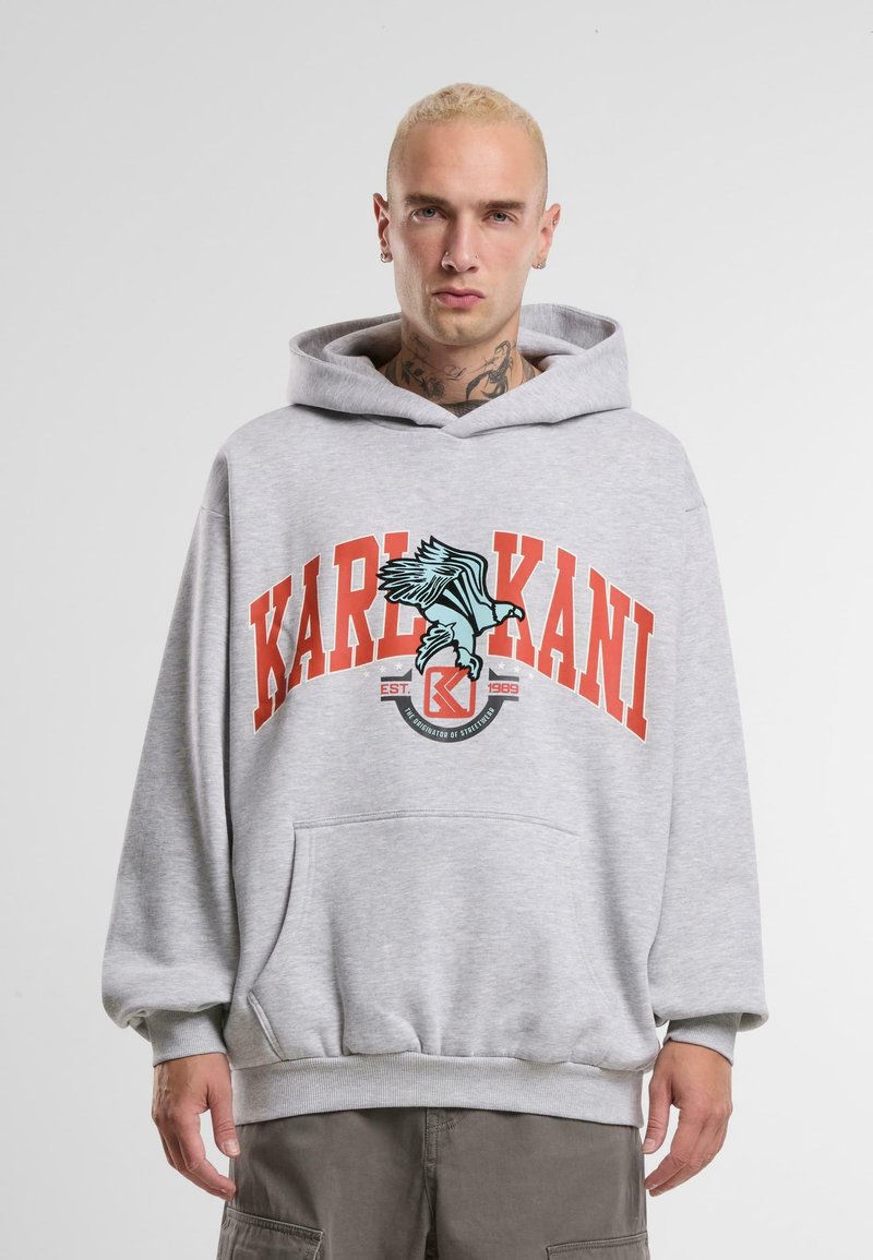 Gray hooded sweatshirt with a front kangaroo pocket, featuring red text "KARL KANI" and a teal bird graphic. Made of soft, textured fabric.