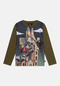 Langermet T-skjorte i mørkeblå og olivengrønn med et LEGO-tema grafikk som viser karakterer på kosteskaft foran et slott.