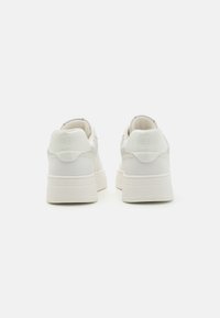 White sneakers with a smooth leather upper, mesh accents, padded collar, and a thick rubber sole. Logo detail on the heel.