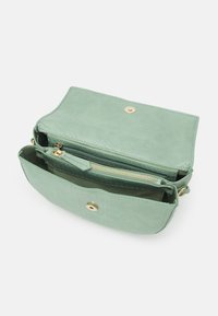 Borsa crossbody verde con texture, chiusura a scatto dorata e scomparto interno con zip, mostrata aperta su uno sfondo bianco.
