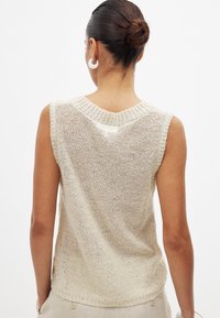 Beige sleeveless knit top featuring a V-neck, open weave texture, ribbed trim, and a relaxed fit, suitable for casual wear.