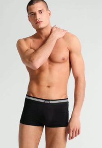 Mustade poksitrükkide lühikesed püksid kontrastsete valgete elastse vööga, millel on kaks triipu; sujuv kangas ja sobiv, modernne lõige.