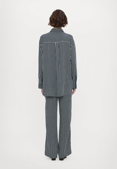 Striped shirt and pants set in navy and white. Loose fit, collared shirt with long sleeves, and wide-leg trousers, featuring vertical stripes.