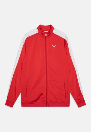 Κόκκινο μπουφάν επιδόσεων με ψηλό γιακά, λευκές πλαϊνές πάνελ, τσέπες με φερμουάρ και μια εξέχουσα λευκή λογότυπο στο αριστερό στήθος.