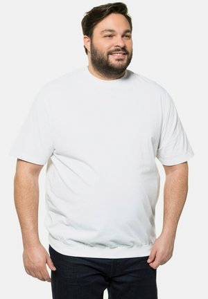 Camiseta blanca de algodón, cuello redondo, mangas cortas, corte relajado, textura suave, ligero estiramiento, combinada con jeans de mezclilla oscura.