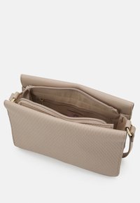 Beige faux læder taske med et struktureret honningkombinationsmønster, der har en lukning med lynlås på toppen og en indvendig lynlås-lomme. Justerbar rem medfølger.