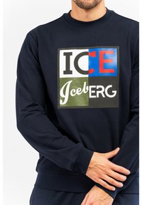 Marineblaues Sweatshirt aus Baumwolle mit einem großen, mehrfarbigen Grafikdruck auf der Vorderseite, der "ICE" und "Iceberg" in unterschiedlichen Schriftarten und Farben zeigt.