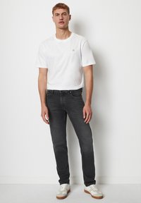 Biała bawełniana koszulka z krótkim rękawem, szare dżinsy o dopasowanym kroju oraz białe trampki z beżowymi akcentami. Prosty i nowoczesny design.