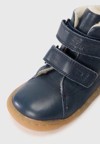 Kék bőr bokacsizma két tépőzárral, gumitalppal és a tetején látható puha, texturált béléssel.