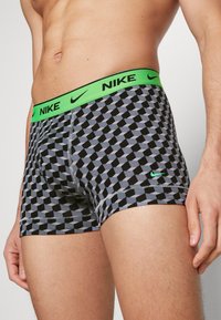 Crne i sive bokserice s geometrijskim uzorkom, istaknute neonsko zelenim pojasom s Nike logotipom.
