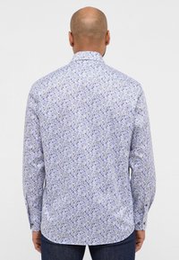 Lange mouw blouse met een blauw bloemenpatroon op een witte achtergrond, gemaakt van katoen, met een klassieke kraag en knoopsluiting aan de manchetten.