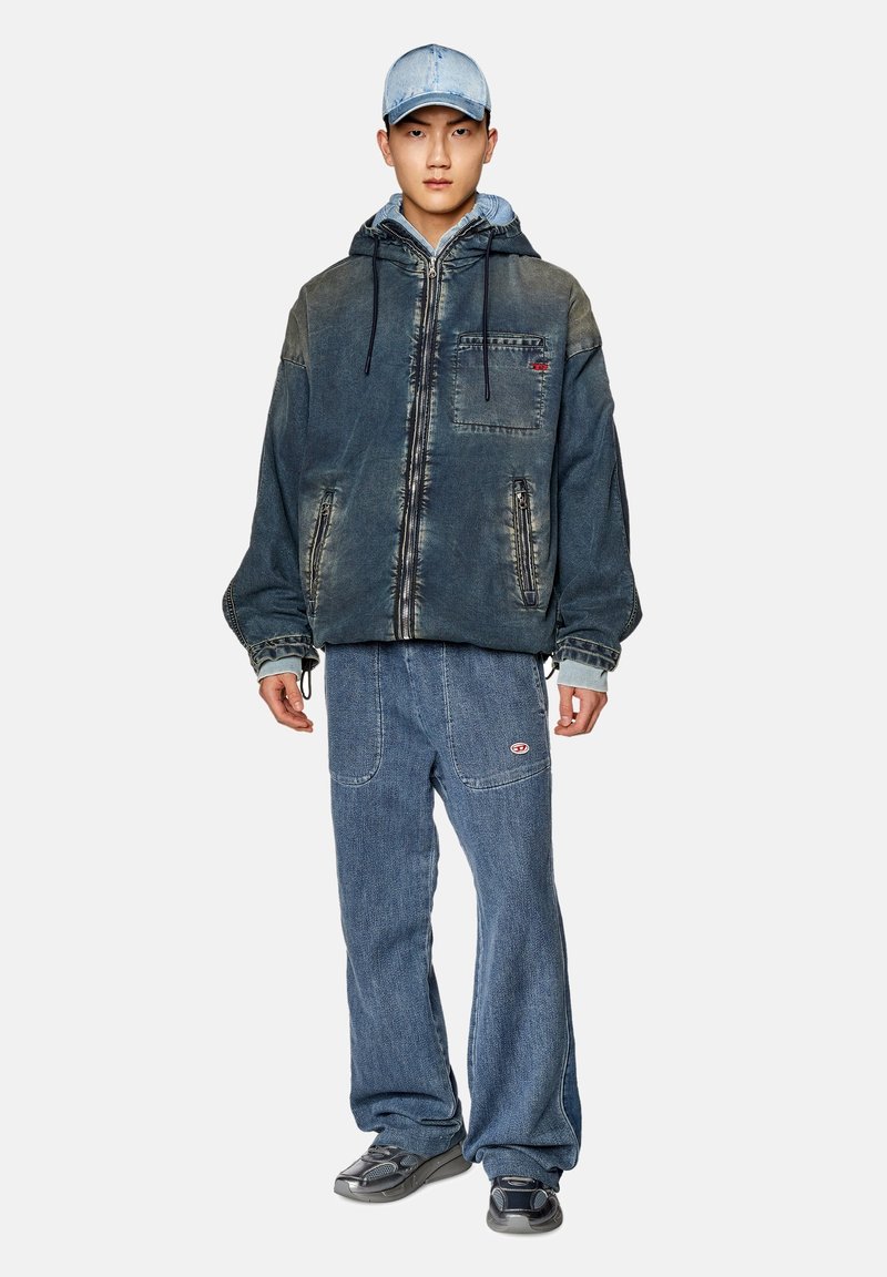 Jeansjacke mit Kapuze und Fronttasche, ausgeblichene dunkelblaue Farbe, kombiniert mit passenden lockeren Jeanshosen und grauen Sneakers.
