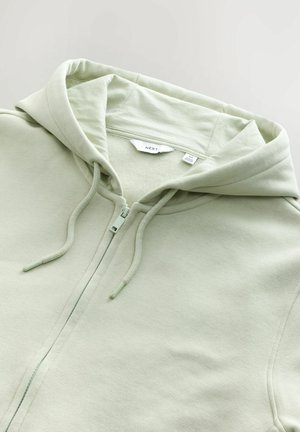 Ljusgrön zip-up hoodie med mjuk textur, som har en huva, dragsko och etikett sydd vid halslinningen.