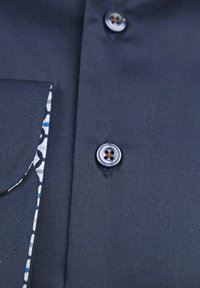 Donkerblauwe shirt met een button-down kraag, een borstzak en een patroonvoering die zichtbaar is aan de rand. Glad, gestructureerd materiaal.
