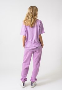 Violets kokvilnas t-krekls ar brīvu piegriezumu un īsām piedurknēm, kopā ar atbilstošām jogger biksēm ar elastīgām aprocēm un kabatām.